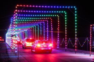Cars travel through rainbow light tunnel at Glittering Lights.